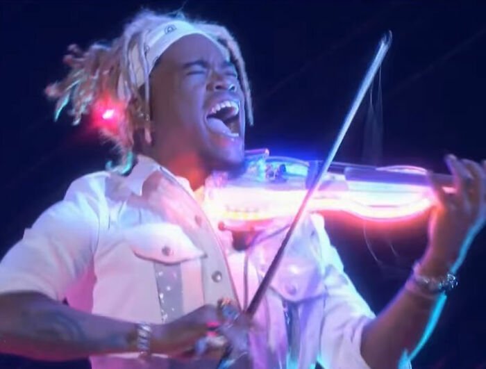 Musician passionately playing neon lit violin on stage, related to Will Smith accused of harassment and grooming lawsuit.