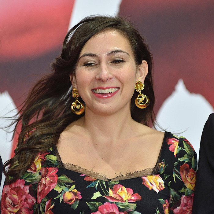 Woman smiling with floral dress and gold earrings, related to new theory after 911 call reveals code word in Victoria Jones case.