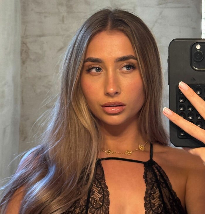 Adult star taking a selfie, showcasing her long hair and makeup, linked to viral 1,000 men in 12 hours challenge.