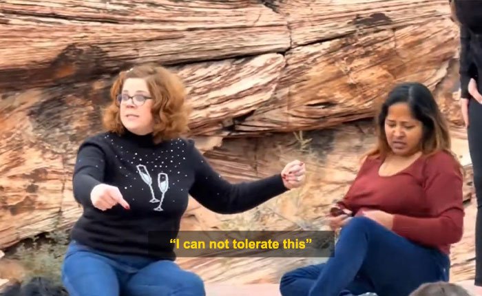 Woman blocking tourist’s shot at Red Rock Canyon during viral First Karen of 2026 incident, seated on rocky ground.