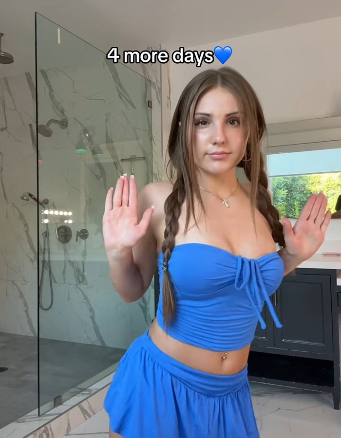 Teen influencer posing in a blue outfit inside a modern bathroom, promoting app debut that sparked concerns.