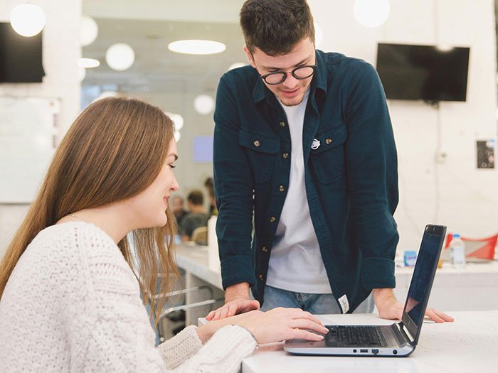 Woman puts coworker on blast on social media, shocked reaction in office setting with laptop and casual attire