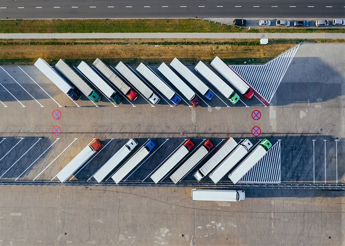 Aerial view of parked trucks at a logistics center representing employee work outside office hours concerns.