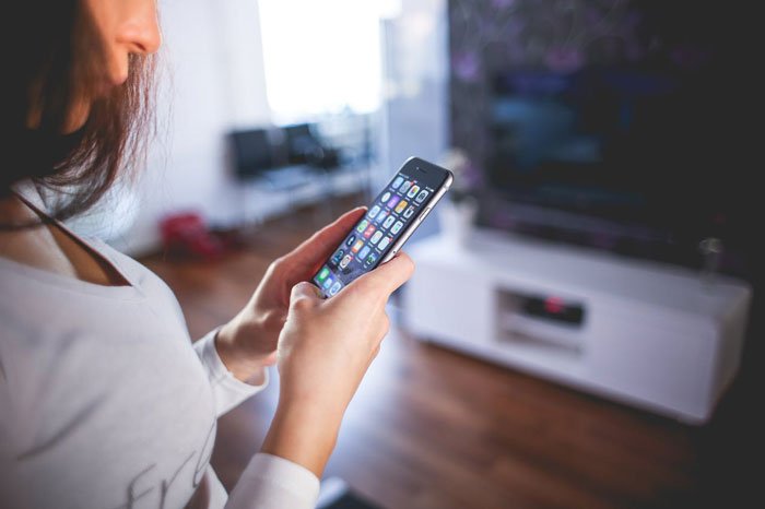 Woman holding smartphone at home, illustrating proof and discovery of cheating and ex-girlfriend drama.
