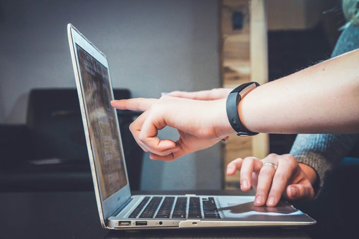 Woman pointing at laptop screen showing proof of cheating while discussing ex-girlfriend's behavior intensely.