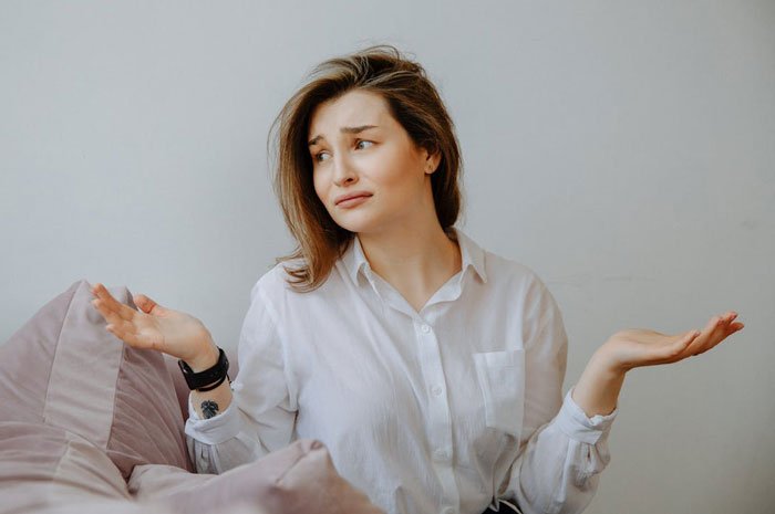 Woman looking confused and distressed sitting on a couch, representing proof of cheating and crazy ex-girlfriends.