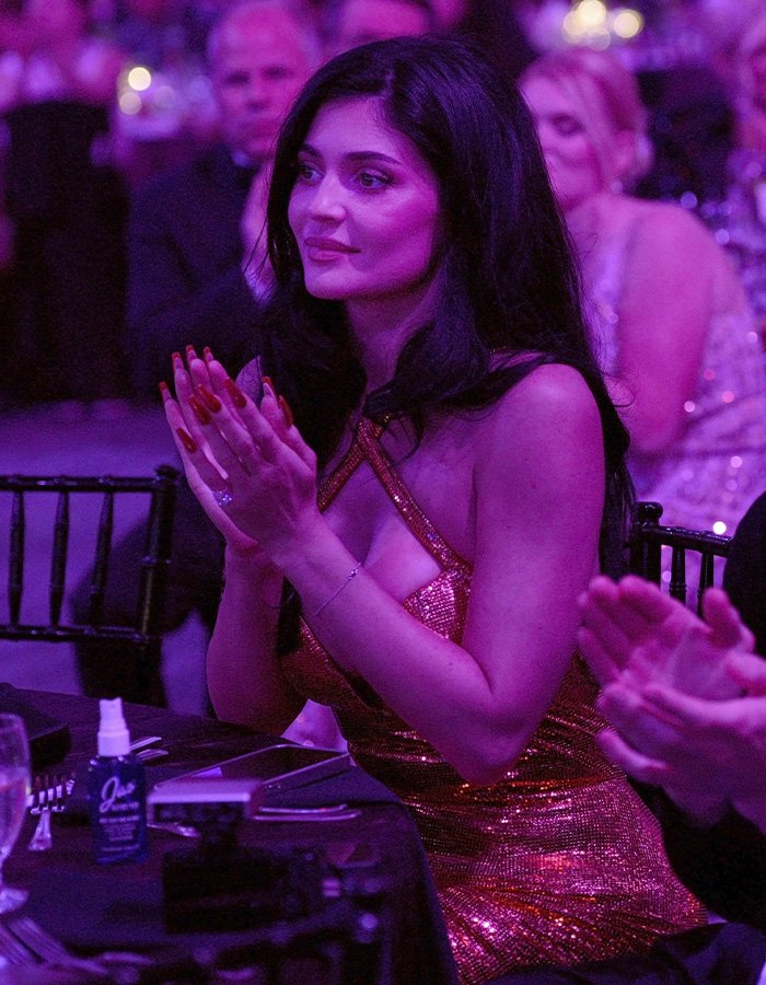 Kylie Jenner wearing a sparkling dress and clapping at an event, sparking buzz with Timothée Chalamet outing.