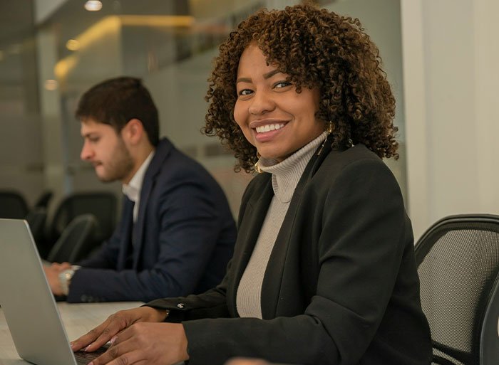 Woman at work smiling nervously while coworker insists on calling her his work mom in an office setting