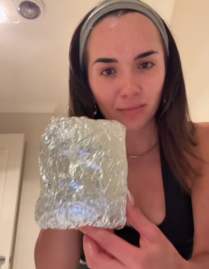 Woman showing a foil-wrapped package brought by Hinge match on their first date, looking stunned and surprised.