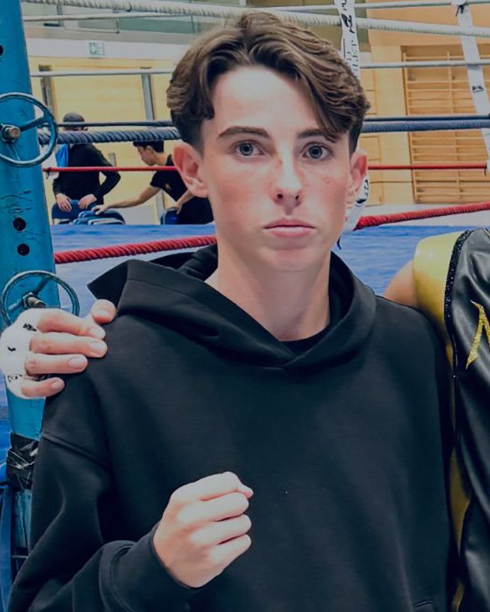 Teenager in a black hoodie with a clenched fist in a boxing ring background, linked to Swiss resort blaze news.