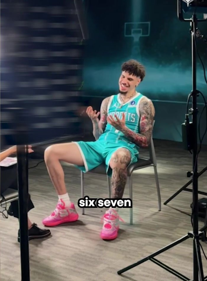 Man in a basketball uniform sitting and laughing during an interview about overused slang words to be banished in 2026.