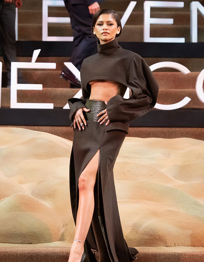 Madame Tussauds wax figure of a celebrity in a black cutout gown posing on steps.