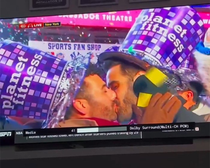 Gay couple kissing on live TV New Year's Eve, wearing Planet Fitness party hats during an ESPN broadcast