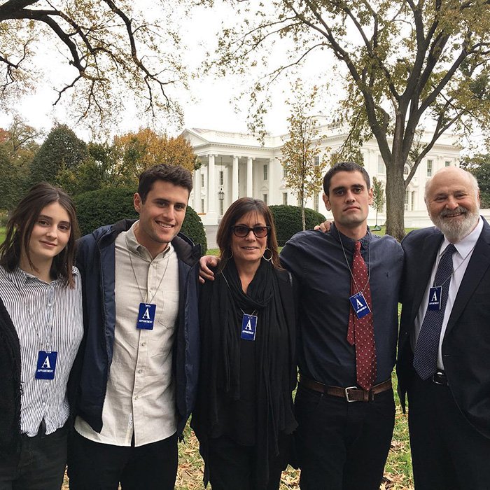 Nick Reiner’s family standing together outside with visitor badges in front of the White House during autumn season.
