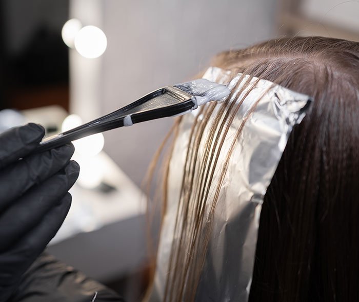 Hair coloring process with foil wraps in a salon highlighting techniques used by a professional stylist discussing Trump’s hair changes.