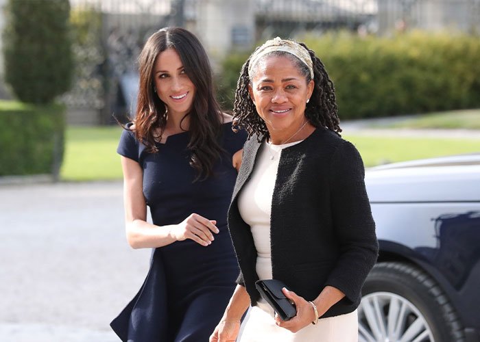 Meghan Markle and her mother Doria Ragland smiling outdoors, sparking alleged rift and wild theories discussion.