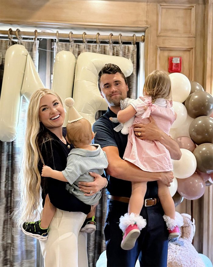 Erika Kirk with family at a celebration, smiling while holding children amid balloons and festive decorations.