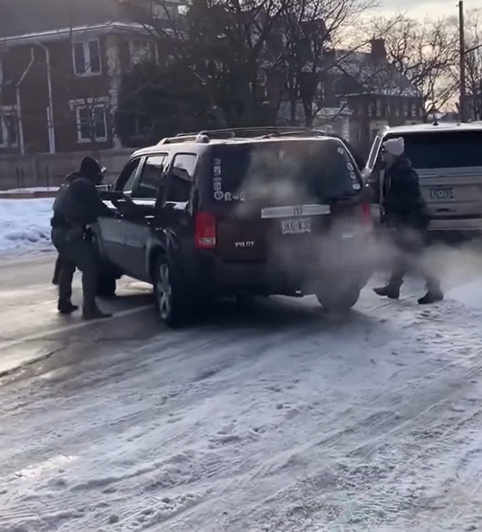 Two individuals in winter clothing near vehicles on a snowy street, relating to Kyle Rittenhouse and ICE slaying news.