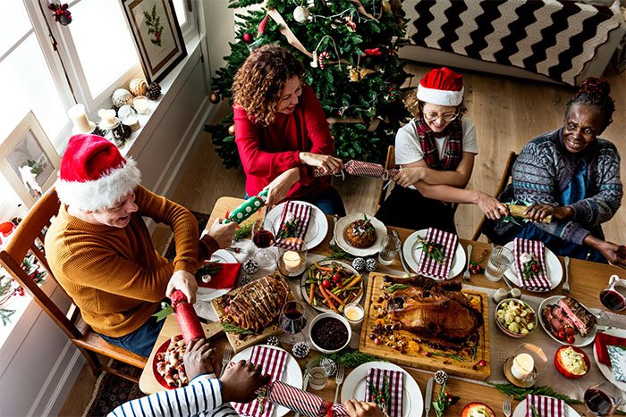 Family gathered at a festive holiday dinner with Christmas tree celebrating but in-laws banned from babysitting over safety concerns