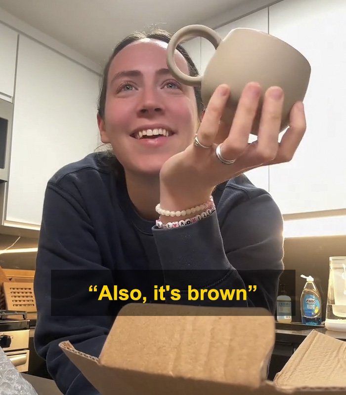 Woman holding up a brown mug gift from fiancé, sparking a huge relationship debate online about the present.