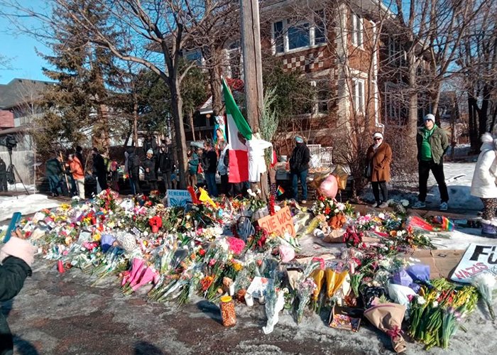 Memorial site with flowers and signs where Renee Good’s wife speaks out on fatal ICE incident in the community.
