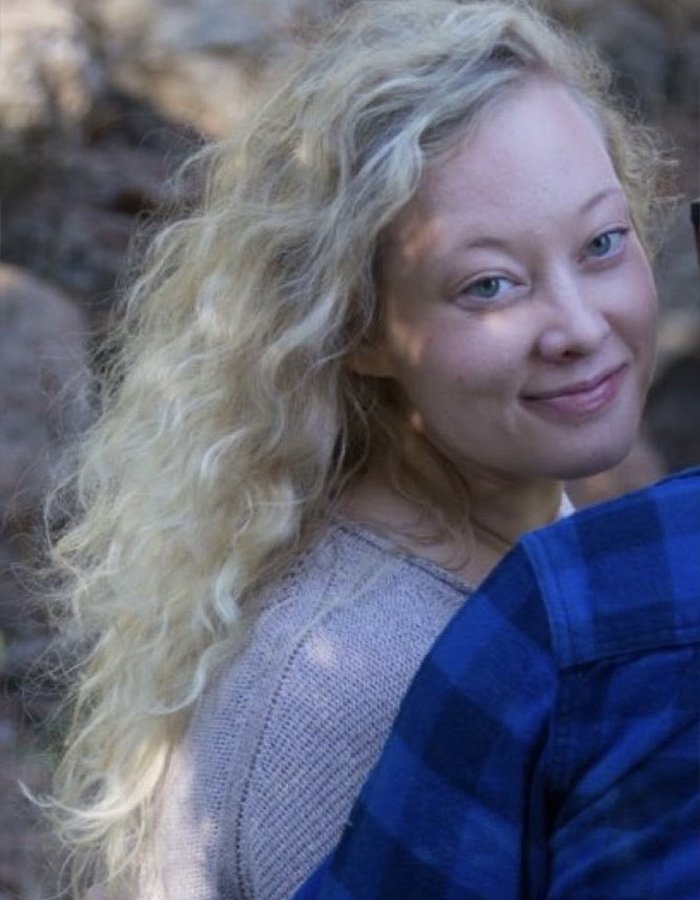 Woman with curly blonde hair smiling softly outdoors, related to Renee Good’s wife breaking silence on fatal ICE incident.