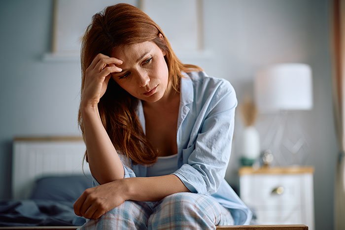 Woman looking distressed and regretful while sitting on a bed, reflecting on stealing 5-year-old niece’s skirt situation.