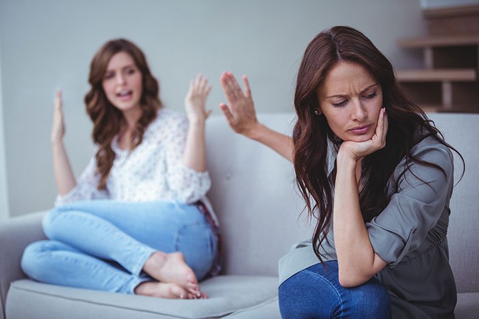 Two women on a couch in a tense conversation, illustrating conflict around woman stealing 5-year-old niece’s skirt.
