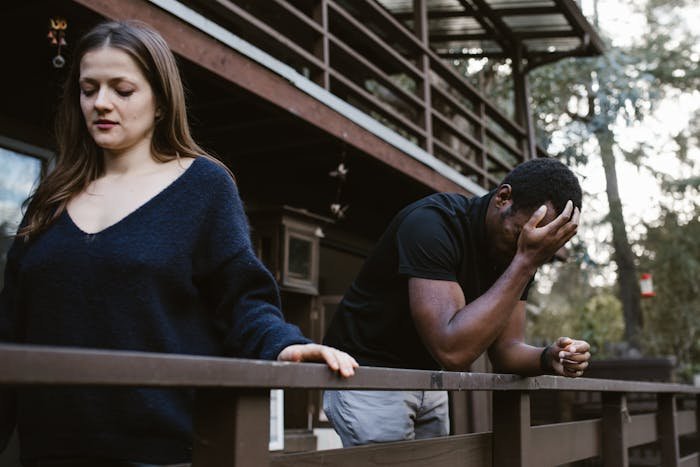 Unemployed woman and jobless man having emotional tension outdoors, reflecting relationship struggles and financial stress.