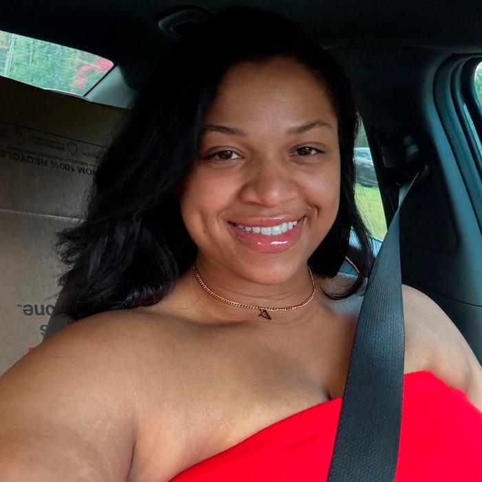 TikTok influencer smiling in car wearing red top and seatbelt after admitting inappropriate act in couple’s home.