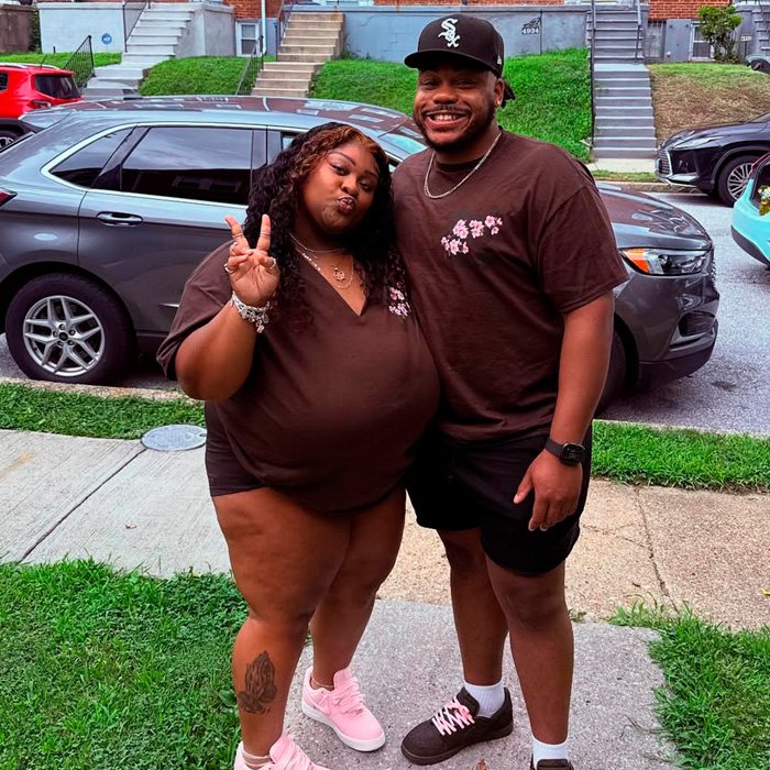 TikTok influencer and friend posing outside near cars, involved in $1.75M lawsuit over inappropriate act in couple’s home.