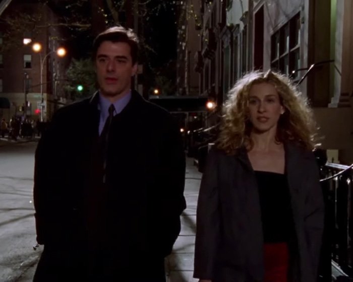 Chris Noth and Sarah Jessica Parker walking on a city street at night in a scene from their acting careers.