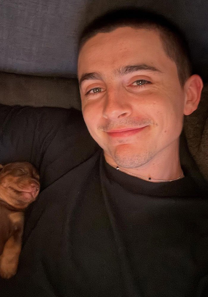 Timothée Chalamet smiling in a selfie while lying down next to a sleeping puppy, related to Golden Globes fight news.