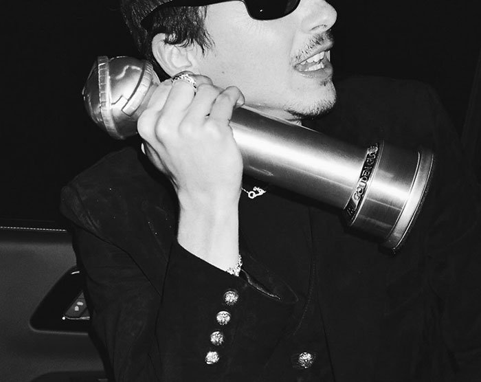 Timothée Chalamet holding a Golden Globe award, dressed in black, reacting during an event amid media attention.