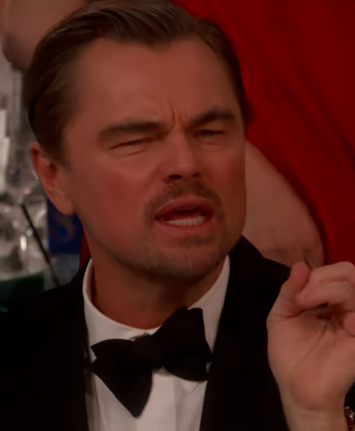 Leonardo DiCaprio in a black tuxedo at the Golden Globes, captured mid-speech during a viral sassy exchange.