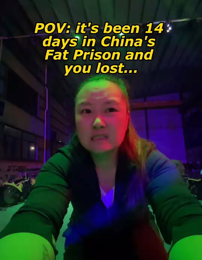 Woman in dark room with colored lighting, sharing experience inside China's fat prison after 14 days of confinement.