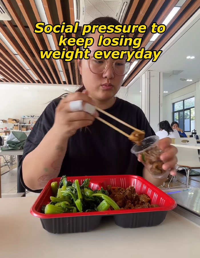 Woman eating a meal in a cafeteria, highlighting social pressure to lose weight every day and fat prison conditions.