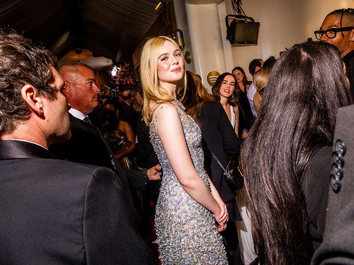 Elle Fanning standing tall in a sparkling gown among a crowd, highlighting women getting bigger in height at Golden Globes.