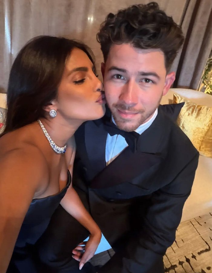 Nick Jonas dressed in tuxedo with a woman kissing his cheek, highlighting Golden Globes 2026 viral moment.
