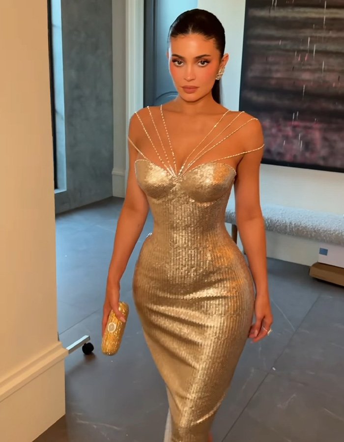 Kylie Jenner wearing a gold dress indoors before the Golden Globes seat photo sparks heated debate online.