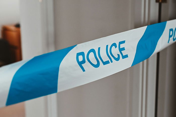 Blue and white police tape blocking entrance, symbolizing reckoning and revenge on coworker in a workplace dispute.