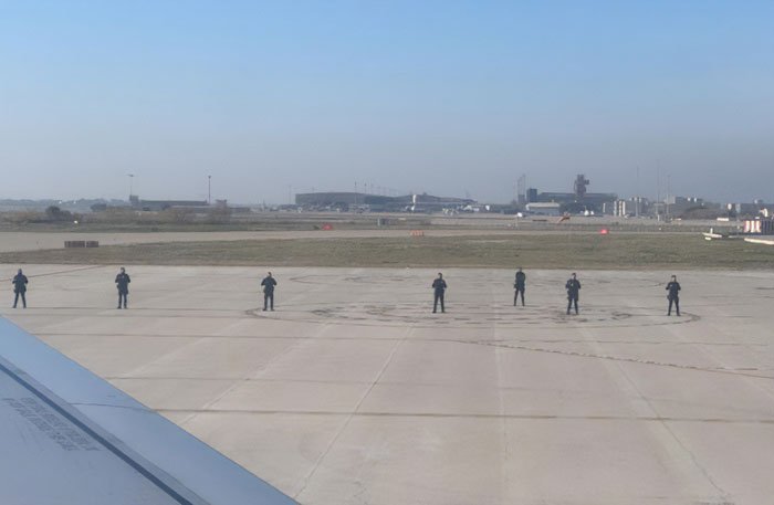 Airport runway with security personnel standing in line as fighter jets scrambled to escort flight over WiFi hotspot issue