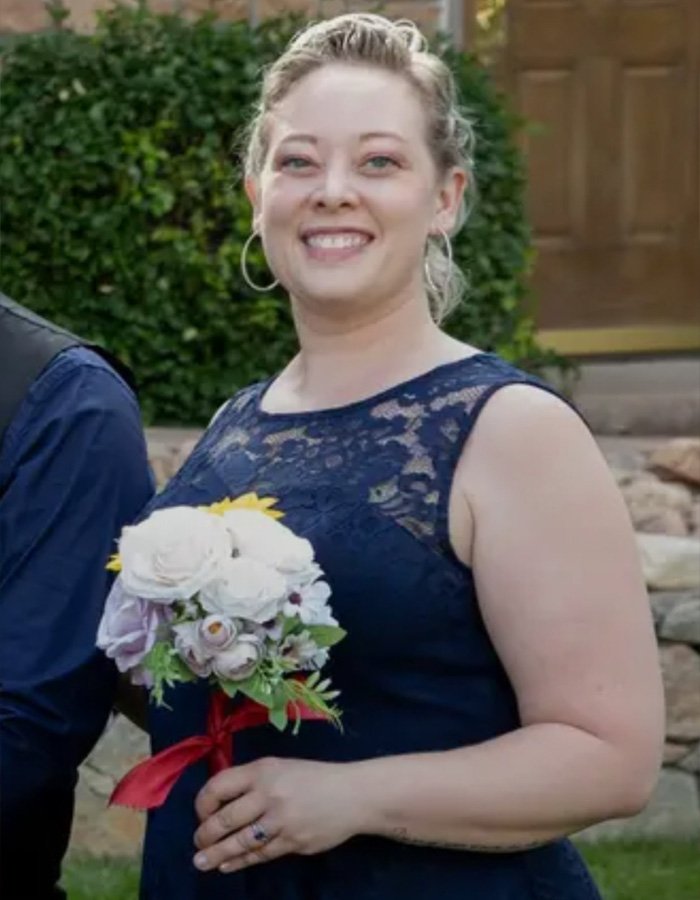 Woman in navy blue lace dress holding a bouquet, smiling outdoors, related to Stephen King faces backlash news.