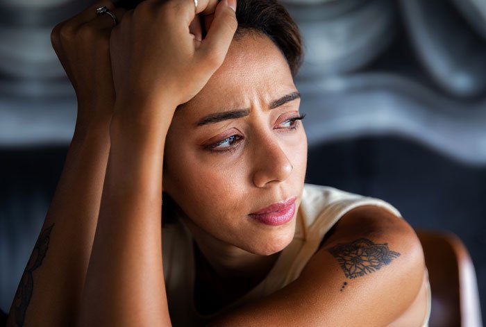 Woman looking distressed indoors, struggling with emotions related to ex’s dog and shelter threats.