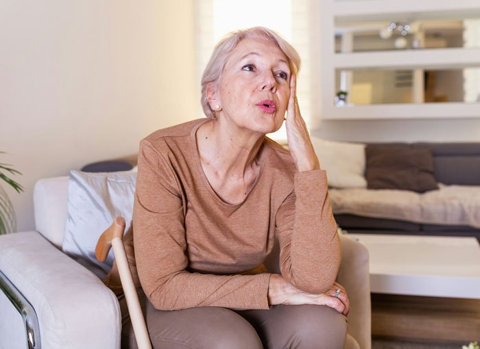 Older woman sitting on a chair looking frustrated in a living room, representing MIL thinking she won against DIL.