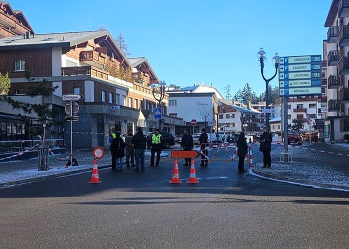 Scene of blocked street in Swiss town with people and officials near cordoned-off area after bar fire incident.