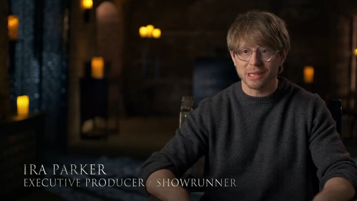 A man wearing glasses and a dark sweater speaks about George RR Martin and a shocking intro scene in A Knight of the Seven Kingdoms.