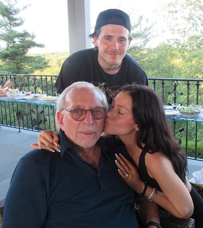 Nicola Peltz showing tattoo with pointed message at Beckham family during outdoor family gathering.