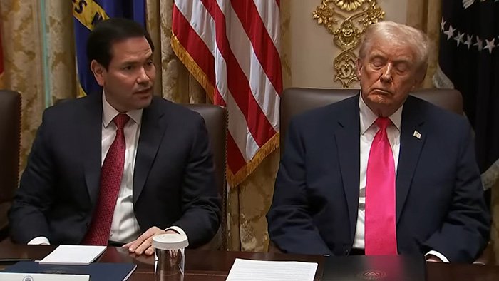 Donald Trump sitting next to a man in a suit, with a visibly droopy face during a formal meeting about health concerns.