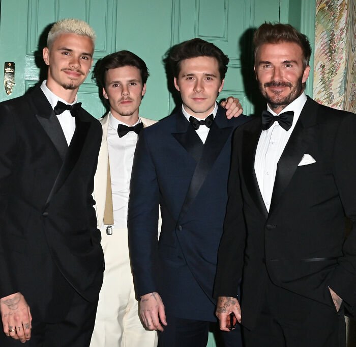Cruz Beckham with family members dressed in formal suits, relating to Brooklyn's claim about Victoria dancing at his wedding.